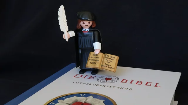 Playmobil-Figur "Martin Luther" steht auf der Bibel