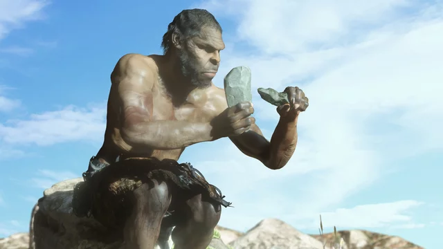 Ein prähistorischer Mensch sitzt auf einem Felsen und bearbeitet einen Stein mit einem weiteren größeren Stein. Er hat einen muskulösen Oberkörper und trägt primitive Kleidung. Der Himmel ist blau mit einigen Wolken im Hintergrund.