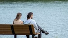 Ein Paar sitzt auf eine Bank am See. 