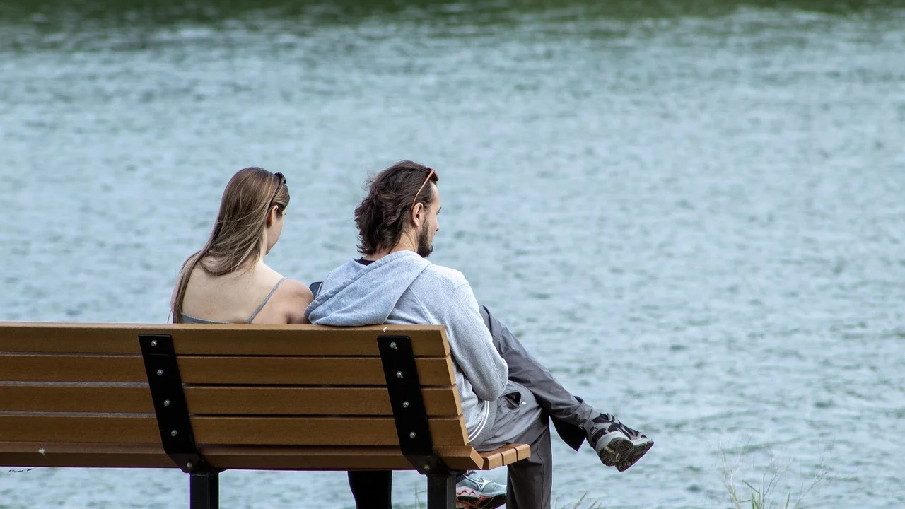 Ein Paar sitzt auf eine Bank am See. 