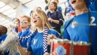 Fußballfans in einem Stadion mit blauen Trikots ihrer Mannschaft. 