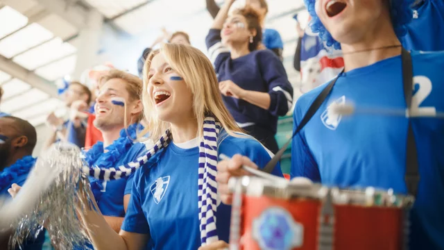 Fußballfans in einem Stadion mit blauen Trikots ihrer Mannschaft. 