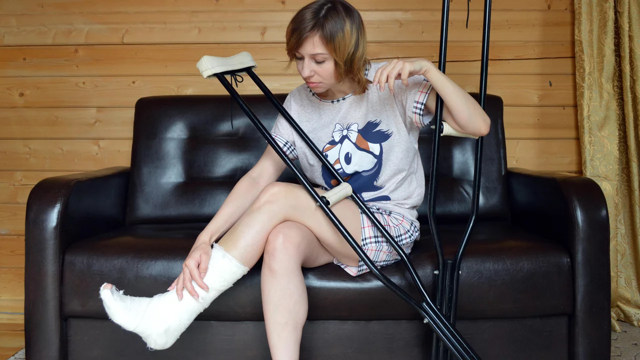 Eine Frau sitzt auf einem Sofa mit bandagiertem Bein. 