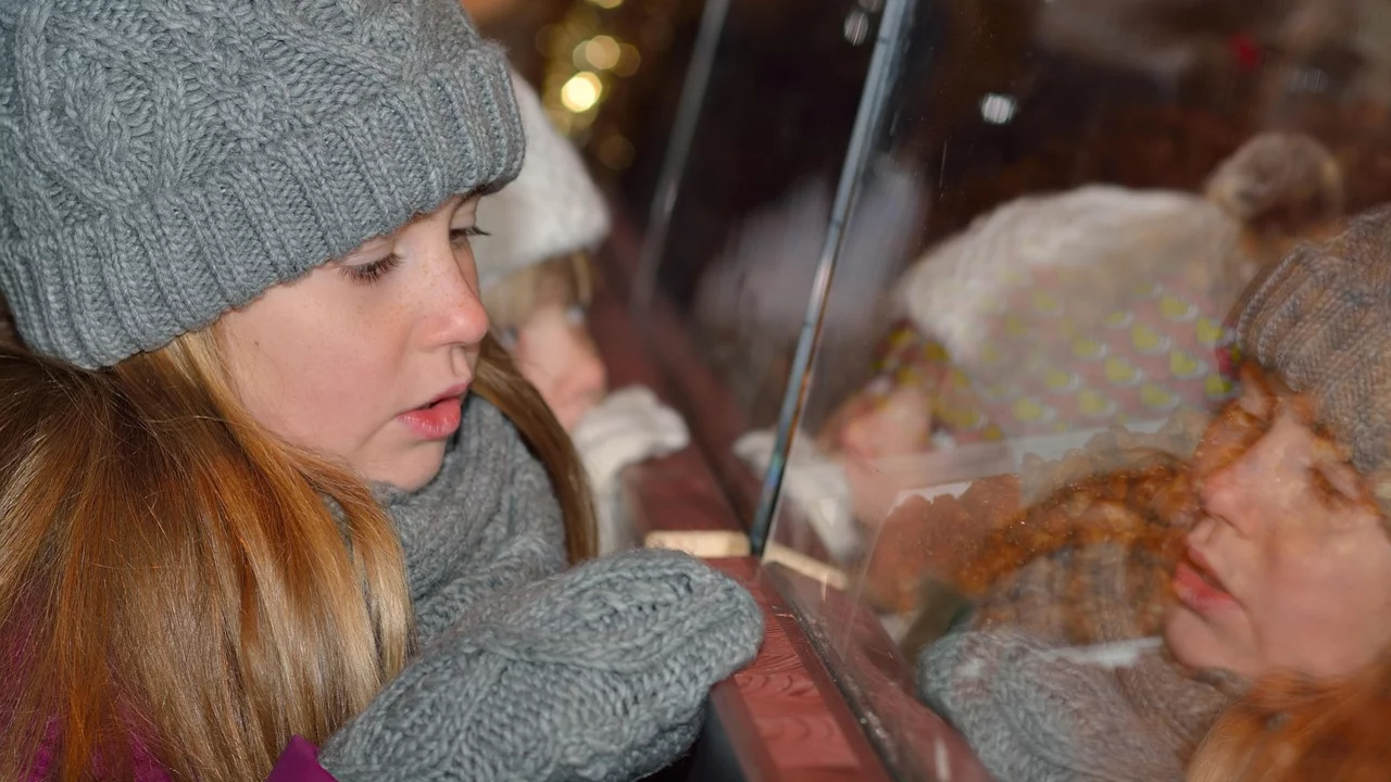 Ein Mädchen schaut neugierig durch ein Schaufenster.