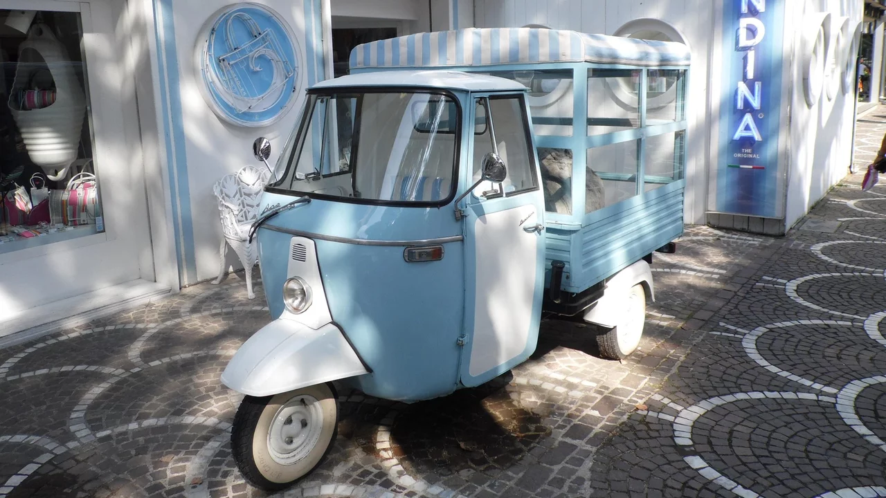 Eine blaue Ape auf der Straße vor einem Geschäft