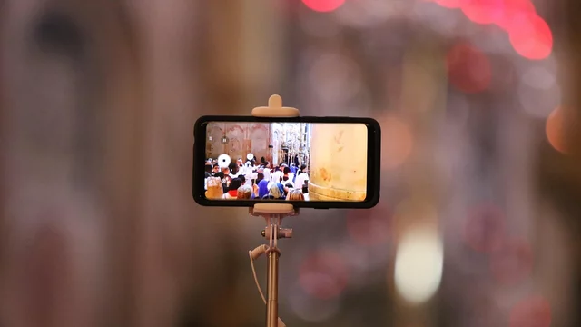 Handy auf einem Stativ, das ein Bild vom Gottesdienstbeginn zeigt