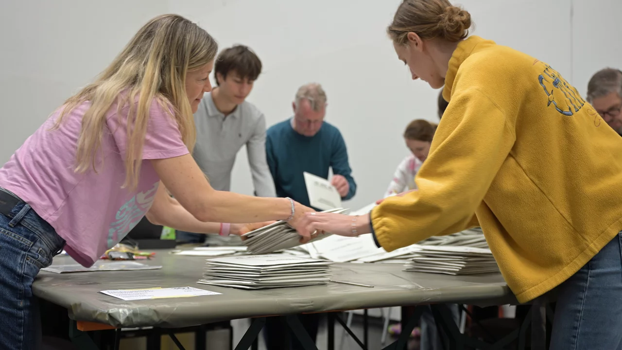 Eine Gruppe von Menschen stehen um einen Tisch und zählen Stimmen aus bei der Kommunalwahl.