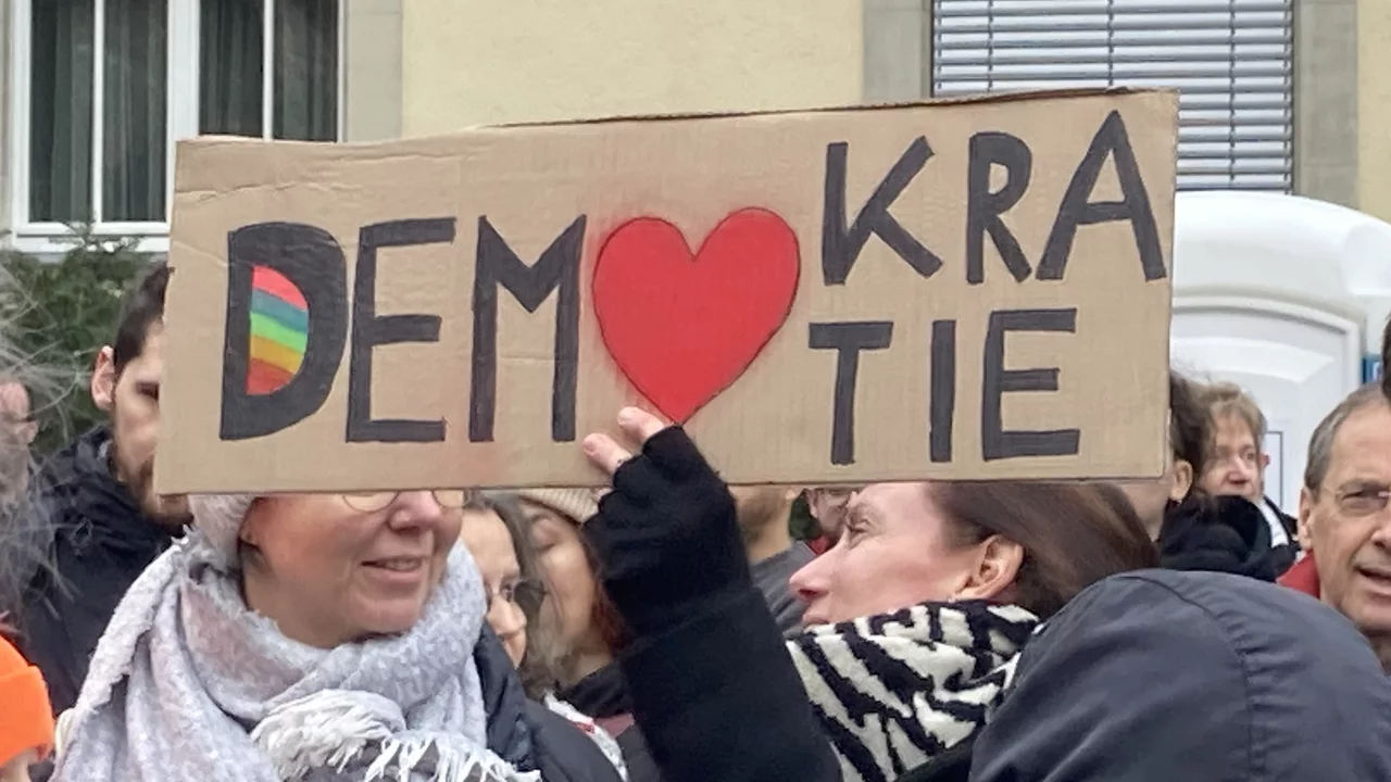Eine Frau auf einer Demonstration mit einem Demokratie-Pappschild