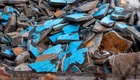 Ein Haufen von abgebrochenen Betonplatten in verschiedenen Farben, vor allem in Blau und Grau. Die Platten sind unordentlich übereinander gestapelt und zeigen verschiedene Oberflächenstrukturen, die durch Abnutzung und Witterung geprägt sind.