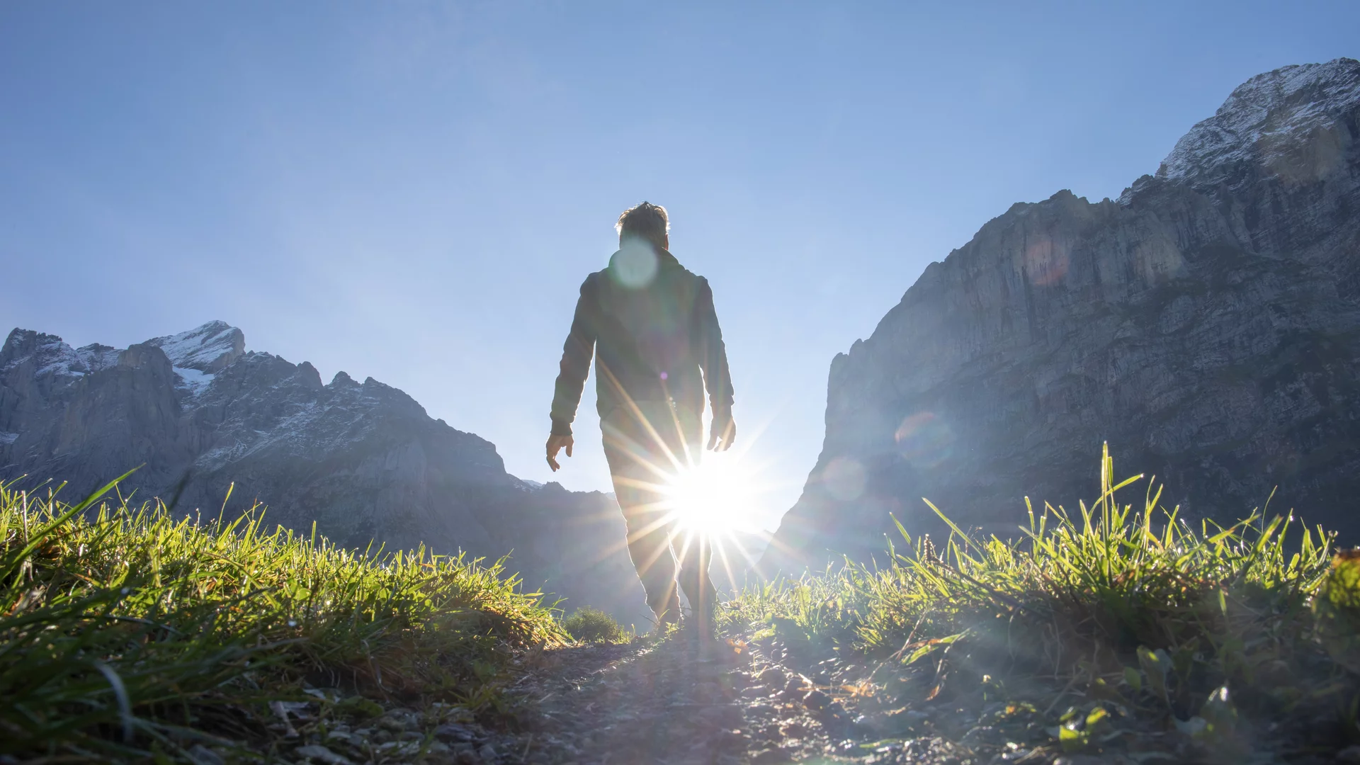 Eine Person wandert in den Bergen an einem sonnigen Tag. 