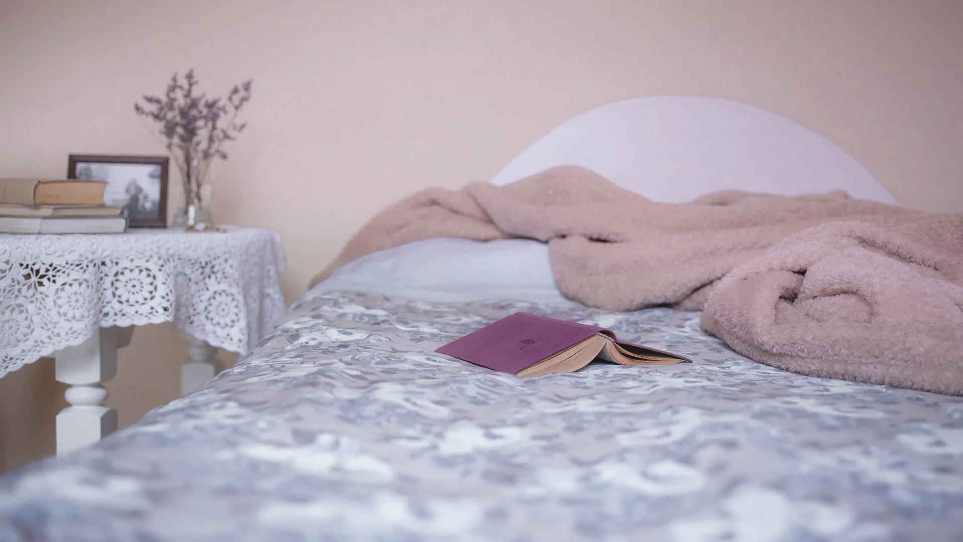 Ein Bett, auf dem ein Buch und eine Decke liegen. 