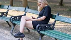 Eine Mädchen sitzt auf einer Parkbank mit seinem Smartphone.