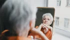 Frau beobachtet sich im Spiegel.