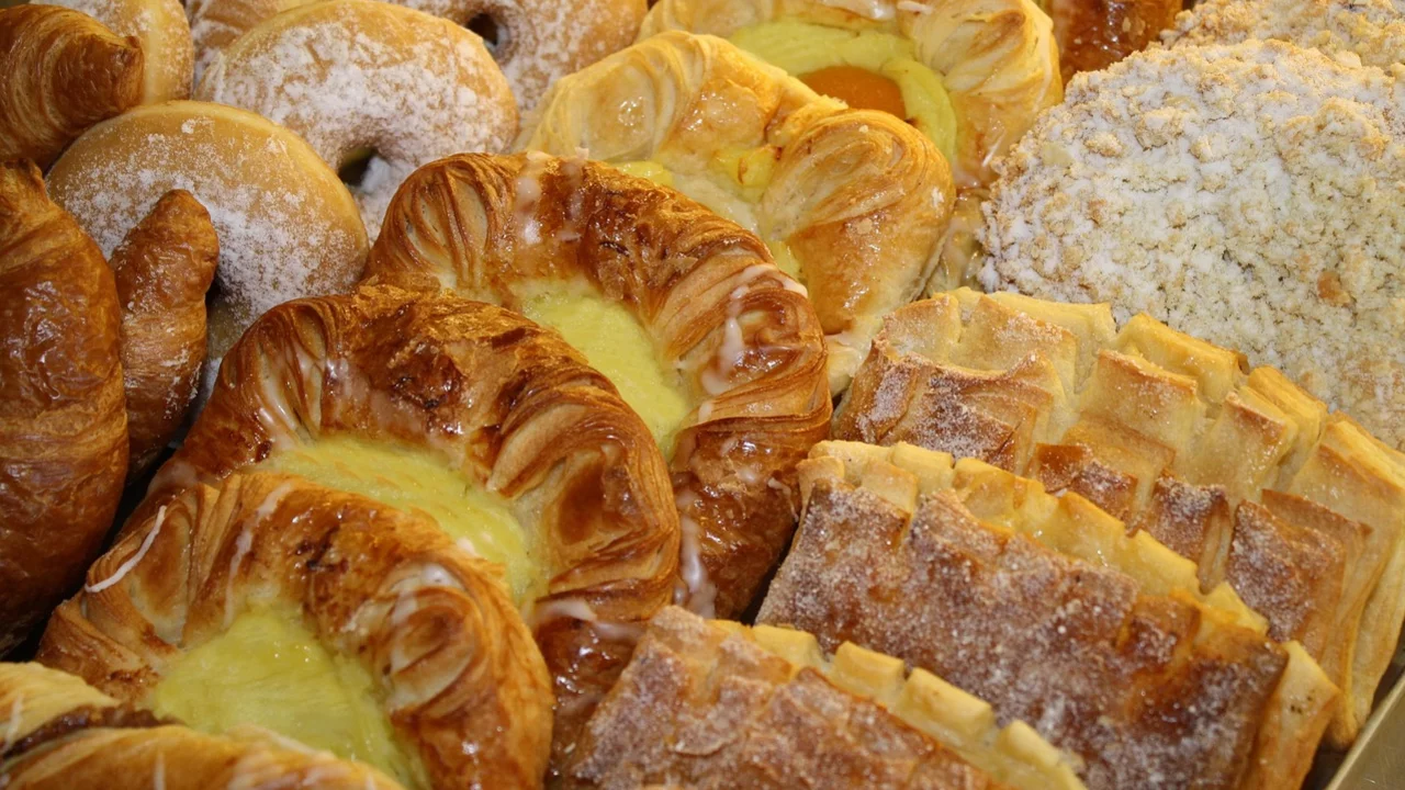 Eine Auswahl an Gebäck ist zu sehen, darunter frische Croissants, gefüllte Teigtaschen und Zimtschnecken. Einige Teile sind mit Zucker bestäubt, andere haben eine cremige Füllung. Die Vielfalt und der ansprechende Anblick machen das Gebäck besonders einladend.
