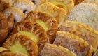 Eine Auswahl an Gebäck ist zu sehen, darunter frische Croissants, gefüllte Teigtaschen und Zimtschnecken. Einige Teile sind mit Zucker bestäubt, andere haben eine cremige Füllung. Die Vielfalt und der ansprechende Anblick machen das Gebäck besonders einladend.
