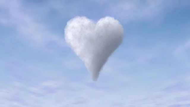 Eine herzförmige Wolke schwebt vor einem blauen Himmel. Die Wolke ist weich und flauschig, umgeben von leichter Bewölkung, die die romantische und verspielte Stimmung unterstreicht.