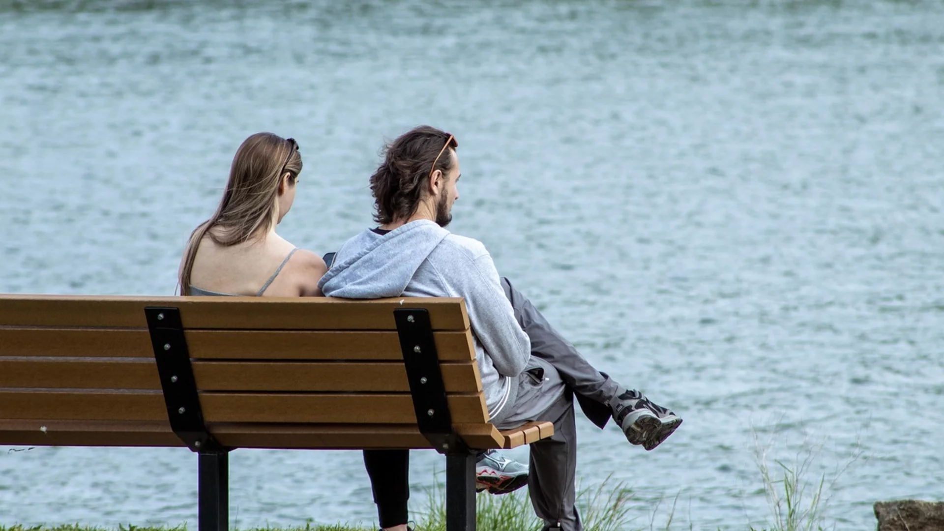 Paar sitzt auf einer Bank am See. 