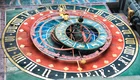Eine detailreiche astronomische Uhr, auf Schweizerdeutsch "Zytglogge", zeigt verschiedene Ziffern und Symbole. Die Uhr hat mehrere konzentrische Kreise und markiert die Tierkreiszeichen. Sie ist von 1405/1406. Sie ist kunstvoll bemalt und befindet sich an einer Wand, umgeben von weiteren künstlerischen Elementen. Diese Uhr steht in Bern, Hauptststadt der Schweiz. 