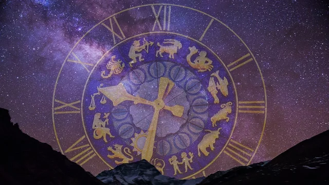 Hinter einem dunklen Gebirgshorizont leuchtet ein sternenreicher Himmel. Im Vordergrund ist ein großes, goldfarbenes Horoskop-Zifferblatt zu sehen, das die zwölf Tierkreiszeichen und die Stundenmarkierungen zeigt. Der Kontrast zwischen Himmel und Zifferblatt vermittelt eine mystische Atmosphäre.