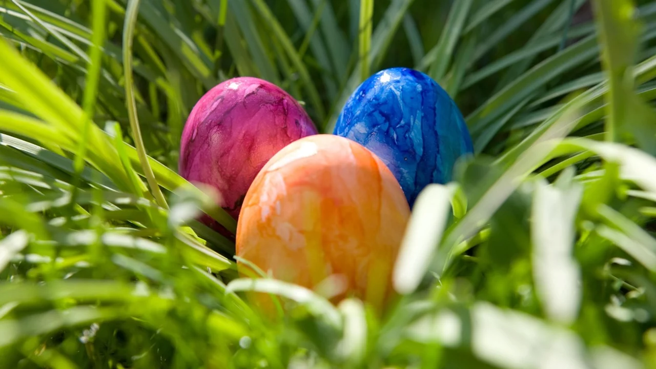Drei bunte Ostereier liegen im Gras.