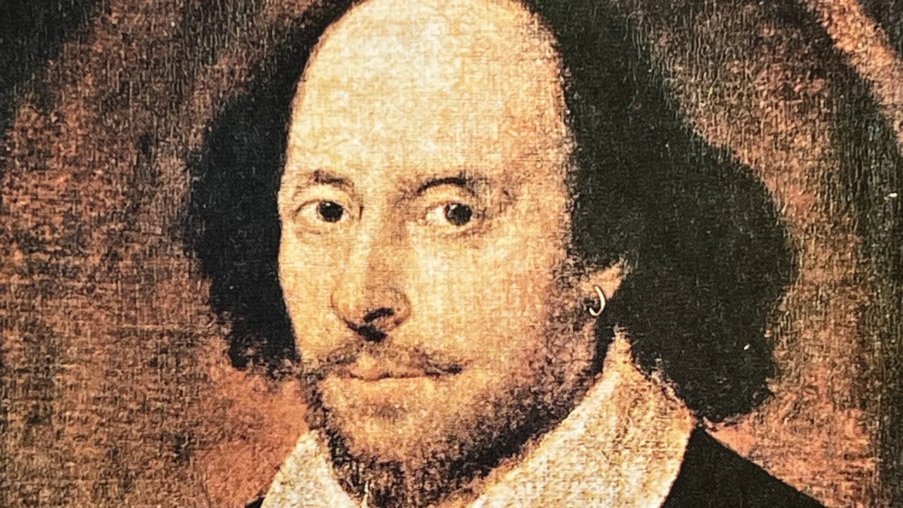 Porträt eines Mannes mit lockigem, schwarzem Haar und einem leichten Bart. Er trägt ein schwarzes Oberteil und einen weißen Kragen. Sein Blick ist ernst, und er scheint direkt in die Kamera zu schauen. Das Bild vermittelt eine historische Atmosphäre. Es soll William Shakespeare darstellen. 