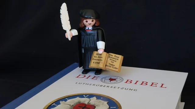Playmobil-Figur von Martin Luther auf einer Bibel.