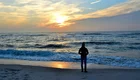 Ein Mann am Meer mit der untergehenden Sonne.