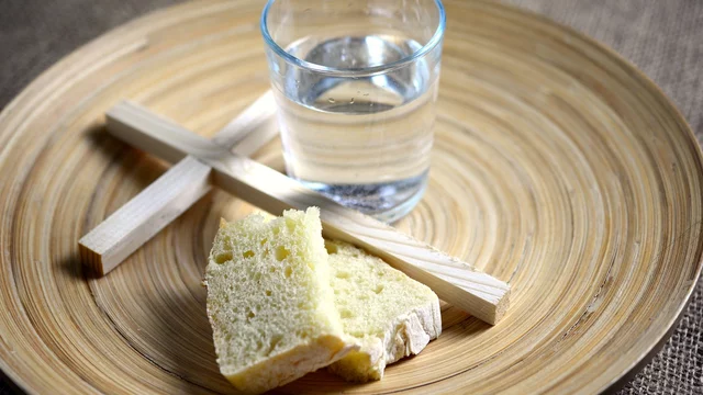 Holztablett mit Brot, Kreuz und Wasser.
