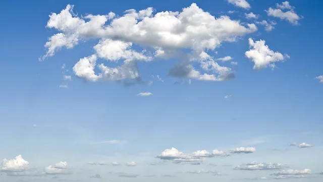 Ein klarer blauer Himmel mit mehreren weißen Wolken, die sich in unterschiedlichen Formen und Größen verteilen. Die Wolken sind weich und flauschig, der Gesamteindruck ist friedlich und einladend.