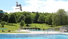 Ein junger Mann springt vom Meterbrett im Freibad.
