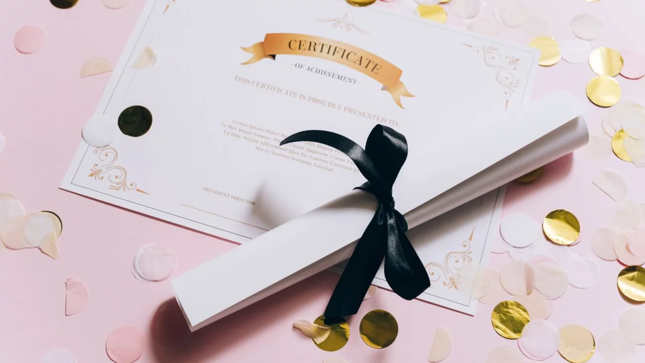 Ein gefaltetes Dokument mit einem goldenen Banner, das "CERTIFICATE" zeigt, liegt auf rosa Untergrund. Neben dem Dokument sind bunte Konfetti-Teilchen in Rosa und Gold verteilt. Das Dokument ist mit einem schwarzen Band zusammengebunden.